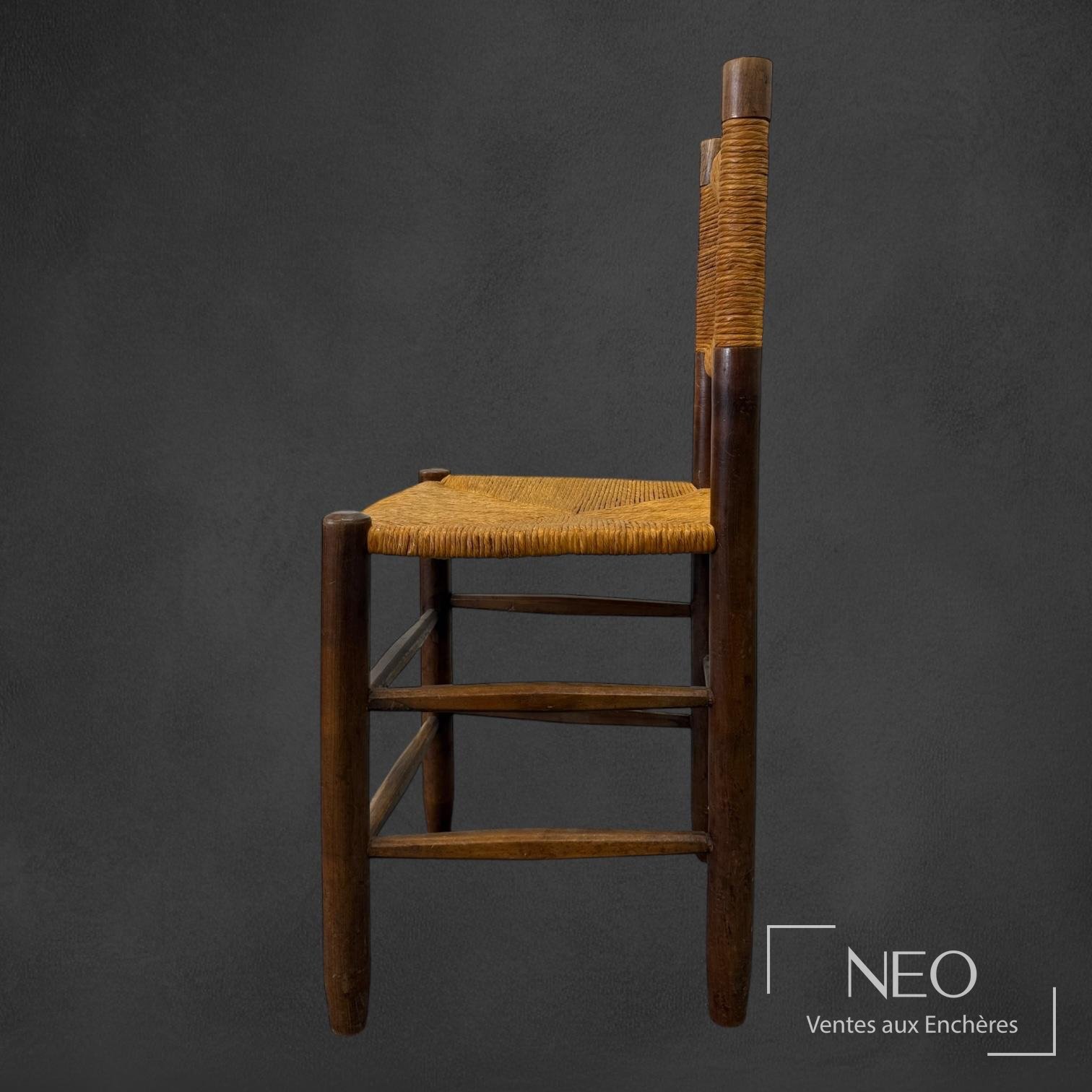 Profil d'une chaise Charlotte Perriand modèle n°18 avec structure en bois et siège de paille