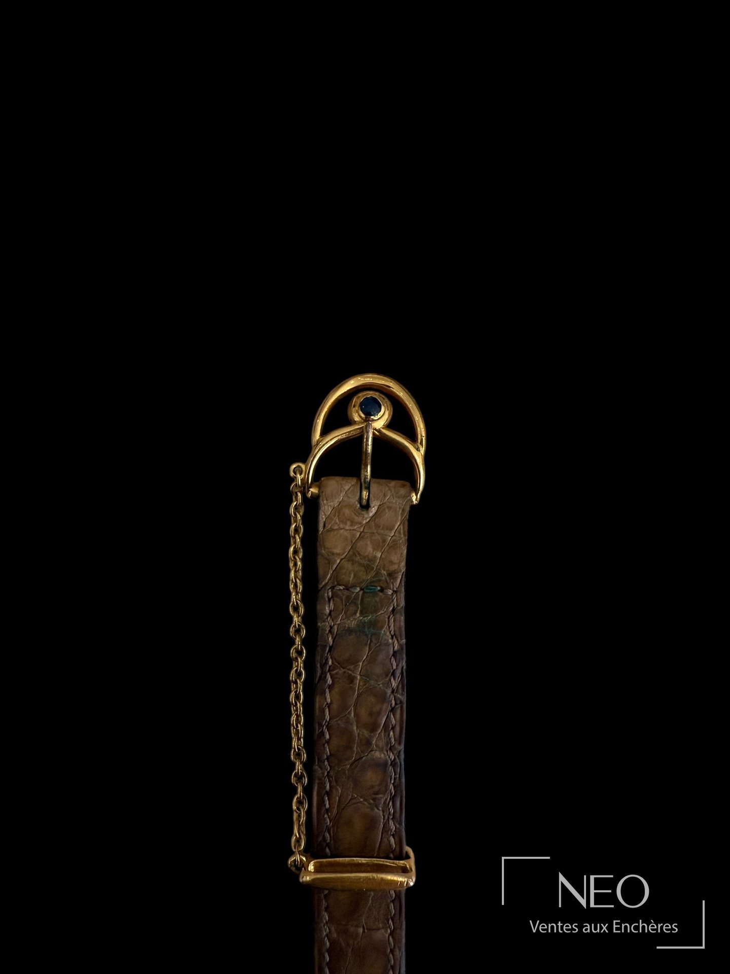 Gros plan sur la boucle ardillon dorée et l'extrémité du bracelet cuir.