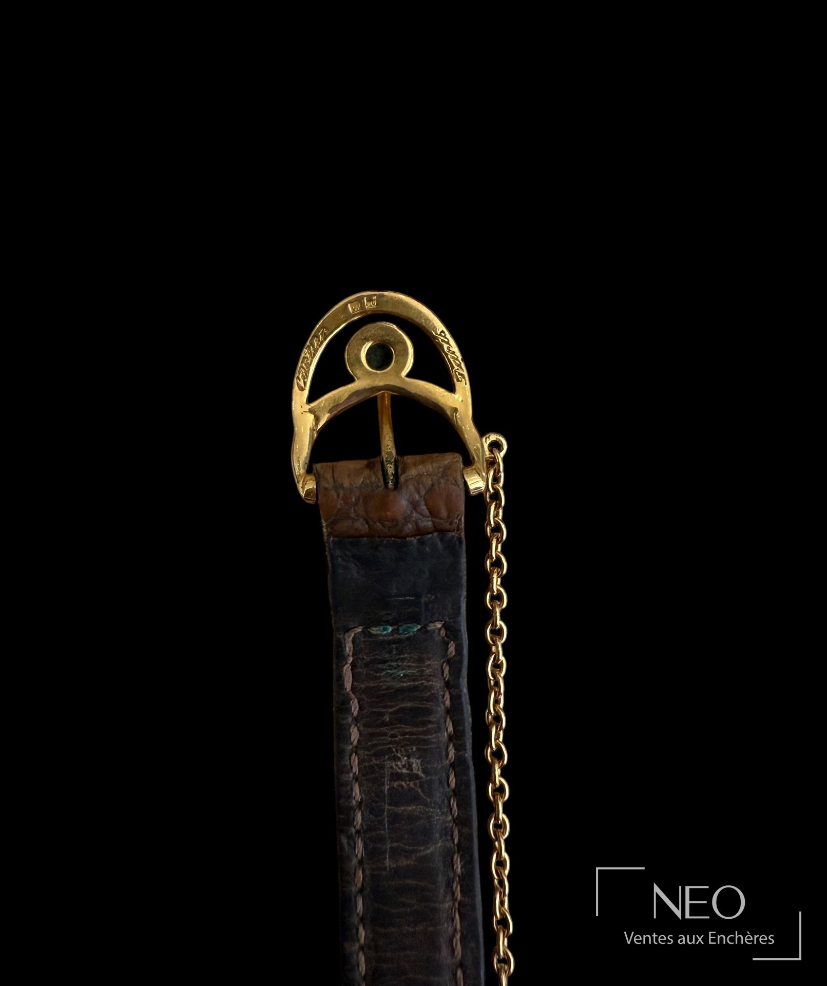 Gros plan sur la boucle du bracelet et sa chainette dorée.