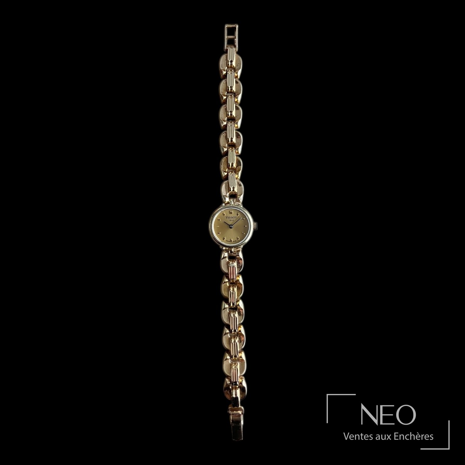 Montre Tissot de profil avec boîtier rond et bracelet en maillons dorés