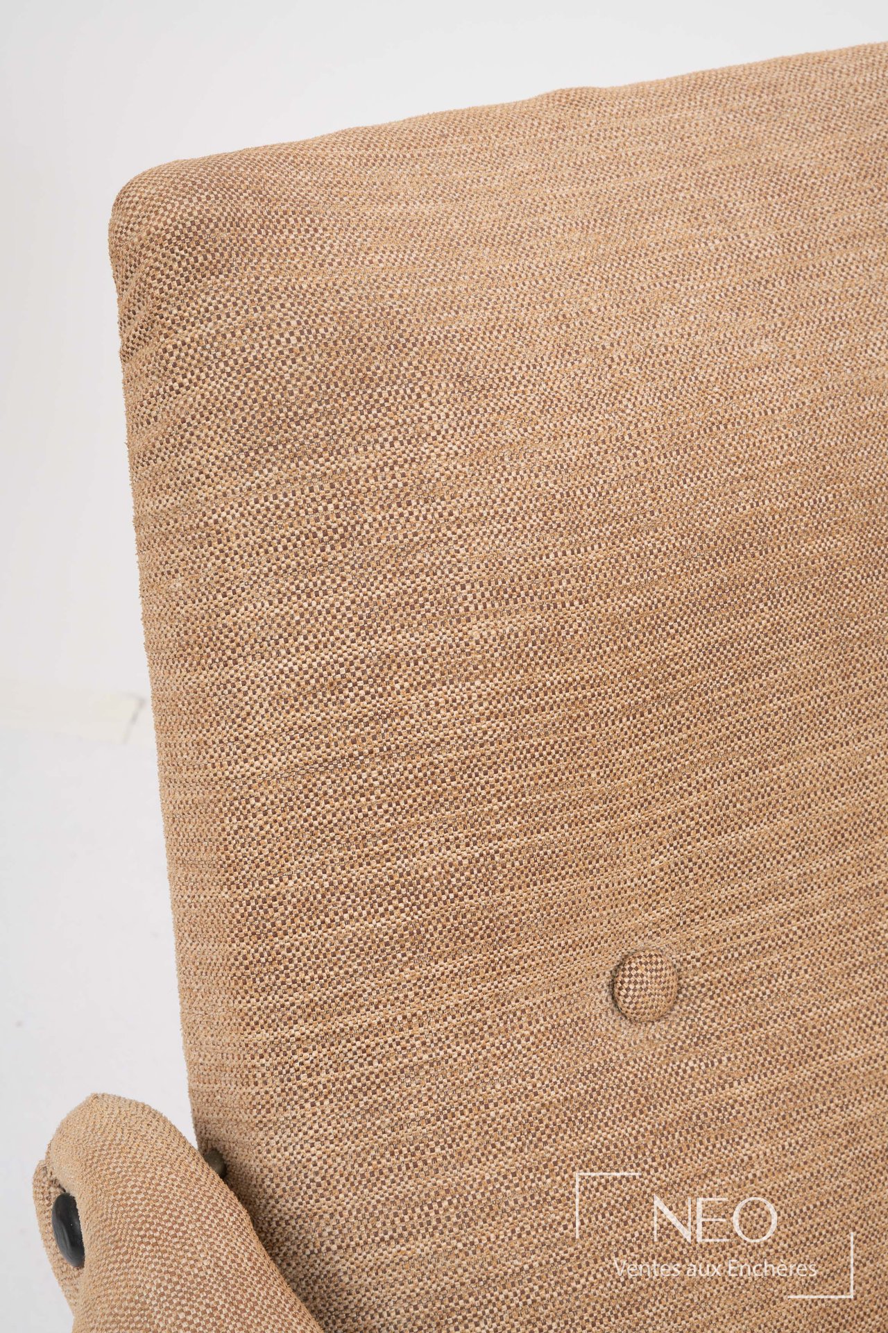 Gros plan sur le dossier d'un fauteuil beige montrant un bouton de capitonnage