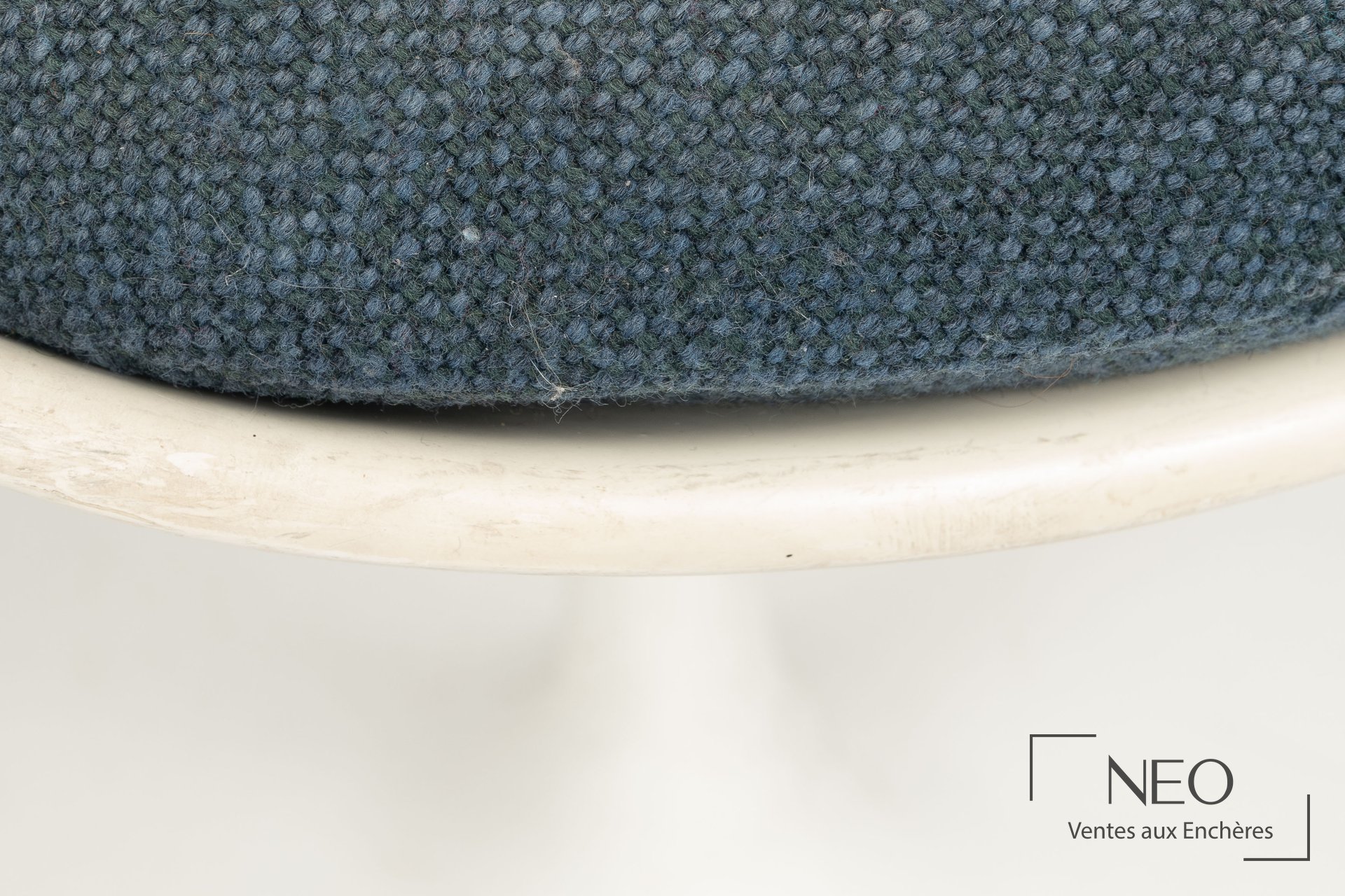 Gros plan sur l’assise en drap de laine bleu et la coque blanche