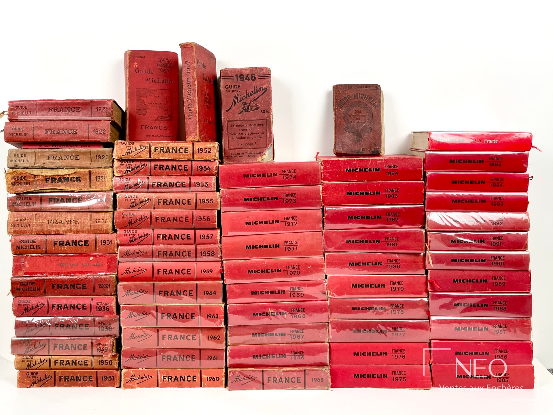 Ensemble de guides Michelin alignés, avec plusieurs couvertures rouges et brunes visibles